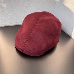 Detailed overhead view of dark red suede-like fabric and neat stitching on newsboy cap