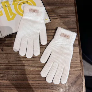 Detailopname van witte gebreide handschoenen met modieus label op een houten bureau