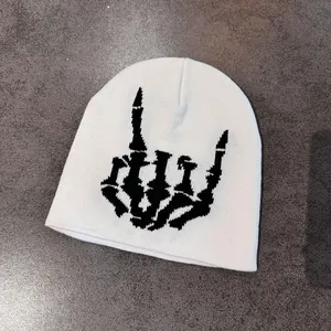 Nahaufnahme einer weißen Rippstrickmütze mit schwarzem Totenkopf-Rock-Hand-Motiv