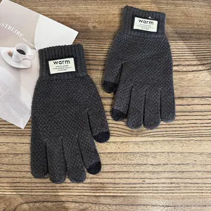 Detail view of dark grey winter knitted touchscreen gloves with ribbed cuffs on wooden table