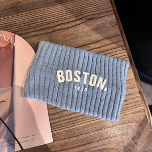 Détail d'un bandeau en maille bleu clair avec écusson Boston 1630 sur fond de bois