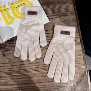 Detail van beige gebreide handschoenen met bruin label op een houten tafel achtergrond