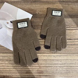 Detail of brown knitted gloves with touchscreen tips and warm ribbed cuffs on wooden desk