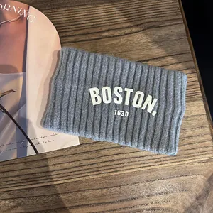 Gros plan d'un bandeau en tricot gris avec broderie BOSTON sur bois vintage