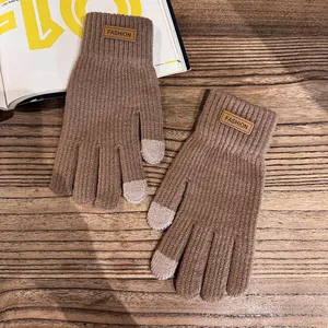 Detail of dark brown cable knit gloves with touch screen fingertips and leather fashion patch