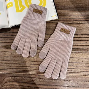 Close-up of knit gloves featuring leather fashion patch and touchscreen fingertips