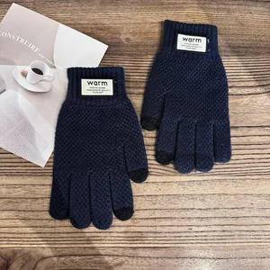 Detail of dark blue waffle knit gloves with touch screen fingertips on wooden background