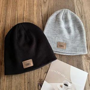 Knitted beanie hat with leather logo patch in black and grey on vintage wood