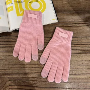Close-up of pink knit touchscreen gloves with fashion label on rustic wooden surface