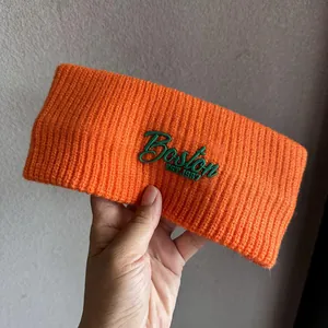 Close-up of orange ribbed knit headband with green Boston 1987 embroidery detail
