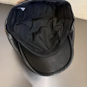 Detail of the black PU leather beret with inner fabric lining and adjustable brown strap