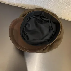 Detail view of the brown knitted newsboy cap featuring a black fabric lining and sweatband