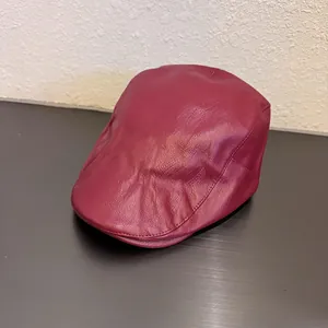 Detail of burgundy PU leather flat cap showing lychee texture and stitching details