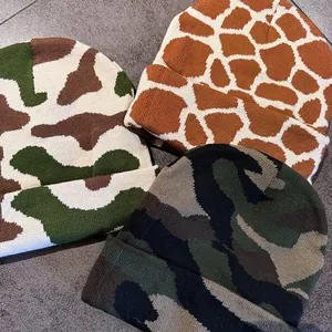 Close-up of three knitted beanies in camouflage, giraffe, and color-block patterns