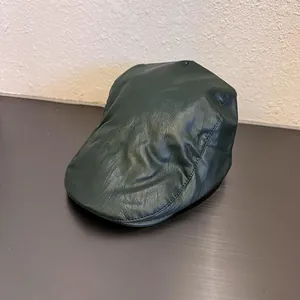 Close-up of deep green faux leather cap showing soft luster and detailed stitching
