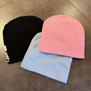 Detail view of knitted beanie hats in black, pink, and blue with skull jacquard patterns
