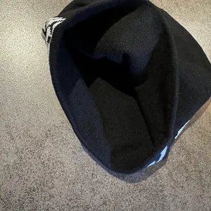 Close-up of the knitted texture and white jacquard pattern on a black skull beanie