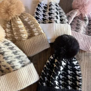 Flat lay of houndstooth knit beanies with fluffy pom poms in various color options