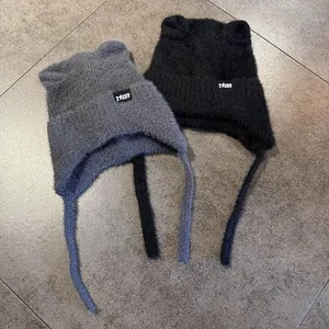 Detalle de los gorros de punto con orejas de gato y lazos largos en color negro y gris