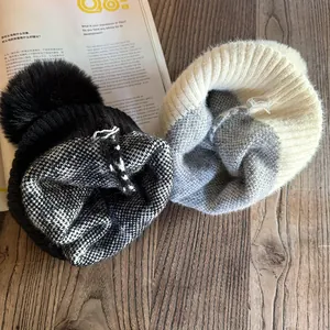 Chic houndstooth knit beanie with large pom-pom on wooden background with magazine