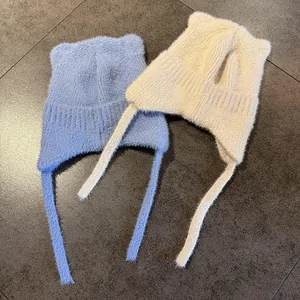 Detalle de gorro de punto con orejas de gato y lazos largos en azul y beige