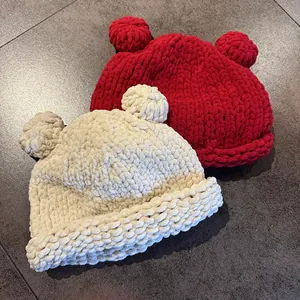 Detail view of chunky knit hats with bear ears in red and beige colors for winter