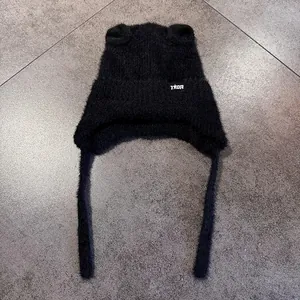 Detalle del gorro de peluche negro con orejas de gato, bordado TX★R y orejeras largas