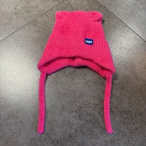Detalle del gorro de punto rosa brillante con orejas de gato, borlas y textura suave