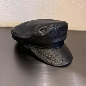 Detail of black faux leather baker boy hat showing textured grain and fine stitching