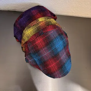 Tres gorras tipo newsboy vintage de cuadros coloridos apiladas en base metálica