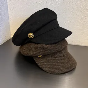 Detail of wool newsboy caps in black and dark brown with golden button accents