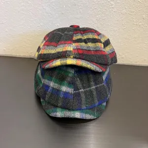 Detail view of colorful plaid wool newsboy caps in red and green textured fabric patterns