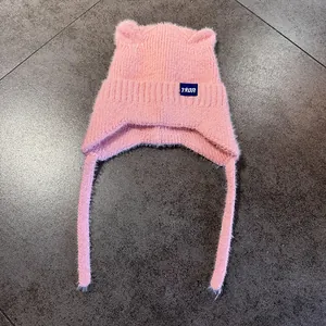 Detalle del gorro de punto rosa con orejas de gato, textura de felpa y etiqueta de la marca