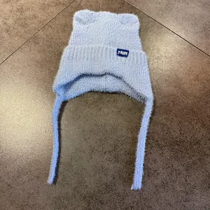 Detalle del gorro de punto azul claro con orejas de gato y cintas para atar bajo la barbilla