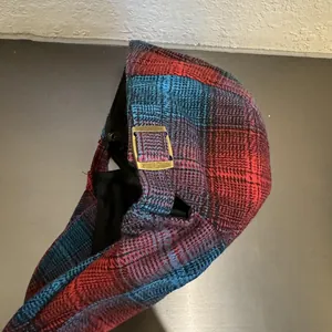 Detalle de gorra vintage de cuadros rojos y azules con hebilla de metal ajustable