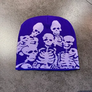Detailed close-up of dark purple knit beanie with white skull jacquard pattern