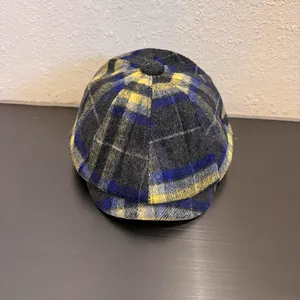 Close-up of a plaid newsboy cap with a yellow and blue checkered pattern and top button
