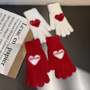 Close-up of soft knit winter gloves with embroidered love heart pattern and plush texture