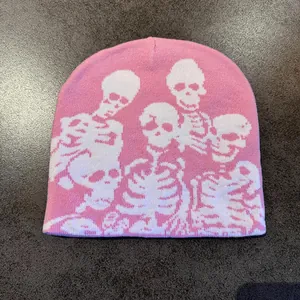 Detail shot of a pink knitted beanie featuring white skull graphic patterns