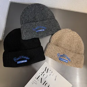 Three warm knitted beanies in black grey and khaki with blue embroidery for women and men