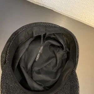 Detail of dark grey baker boy hat showing inner lining and adjustable drawstring