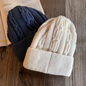 Detailed cable knit pattern on warm winter beanies in navy blue and beige colors