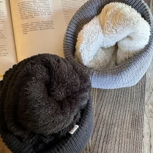 Thick knitted beanie hats with cozy fleece lining in grey and blue on a wooden desk