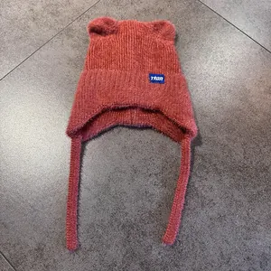 Detalle del gorro de punto rojo con orejas de gato, lana suave y parche de estrella