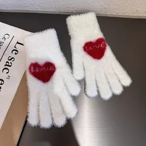 Close-up of white plush gloves with red heart pattern and LOVE text for winter warmth