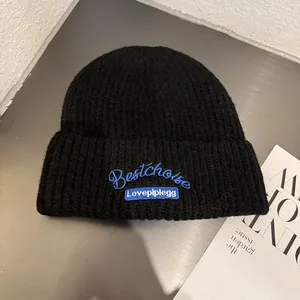 Detailed view of black knit beanie featuring blue Bestchoise embroidery and label
