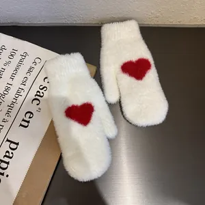 Close-up of white plush mittens with a red heart pattern and soft faux mink texture