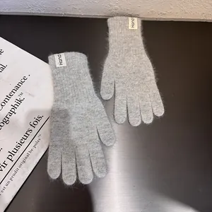 Detail von hellgrauen Strickhandschuhen mit flauschiger Textur und Handm-Etikett
