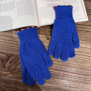 Close-up of blue knit gloves with colorful scalloped cuffs on a wooden background
