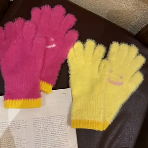 Détail de gants en tricot pelucheux avec motifs smiley en rose et jaune vif